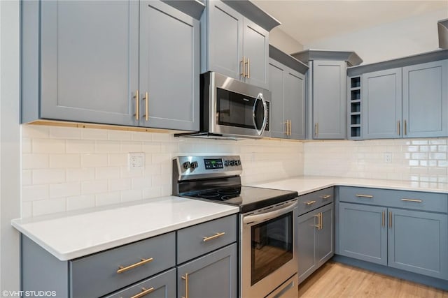 kitchen with tasteful backsplash, stainless steel appliances, and light wood-type flooring