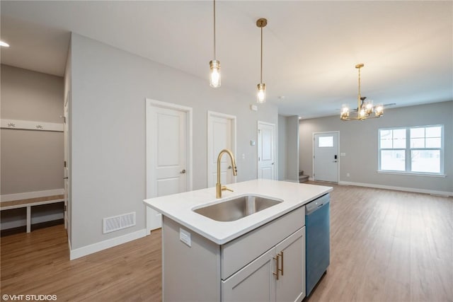 kitchen with decorative light fixtures, dishwasher, an island with sink, sink, and light hardwood / wood-style flooring