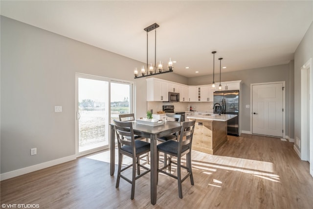 dining space featuring light hardwood / wood-style floors, a notable chandelier, and sink