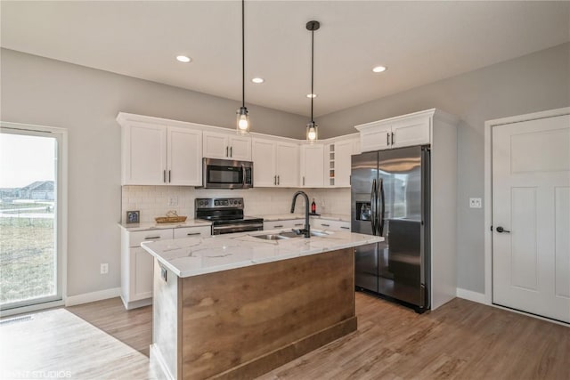 kitchen featuring white cabinets, a center island with sink, appliances with stainless steel finishes, pendant lighting, and sink