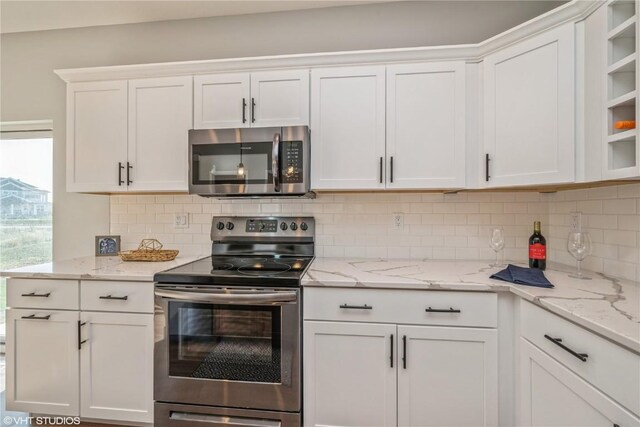 kitchen with decorative backsplash, white cabinetry, and stainless steel appliances