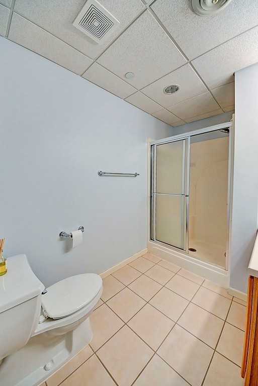 bathroom with tile patterned flooring, walk in shower, vanity, and toilet