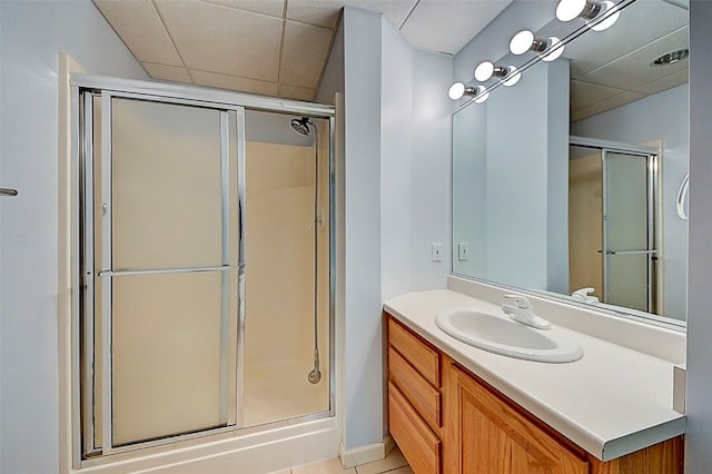 bathroom featuring walk in shower, vanity, a paneled ceiling, and tile patterned flooring