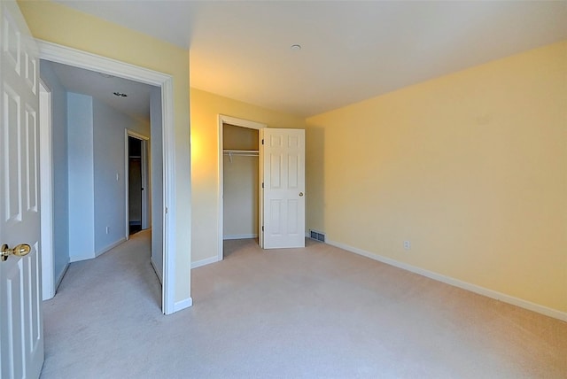 unfurnished bedroom featuring light carpet and a closet