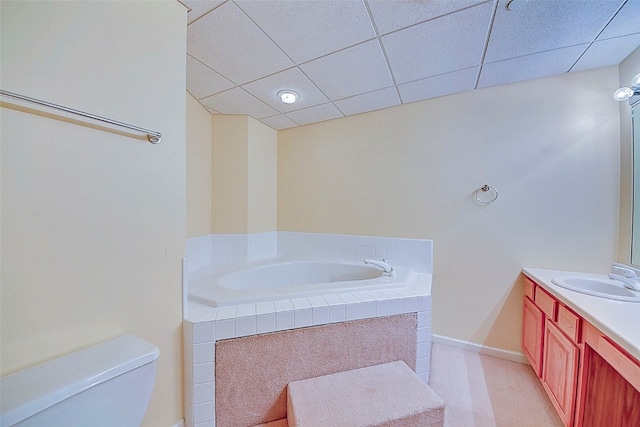 bathroom with a drop ceiling, a bathtub, vanity, and toilet