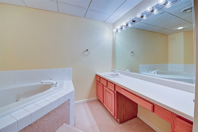 bathroom with vanity, tiled bath, and a paneled ceiling