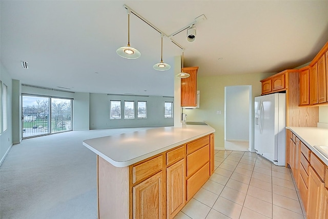 kitchen featuring a kitchen island, white refrigerator with ice dispenser, sink, light tile patterned flooring, and hanging light fixtures