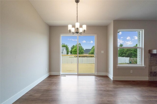 unfurnished dining area featuring hardwood / wood-style flooring, plenty of natural light, and a notable chandelier