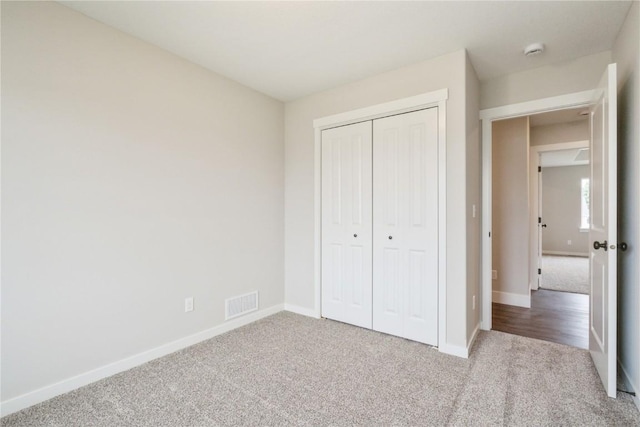 unfurnished bedroom featuring light carpet and a closet