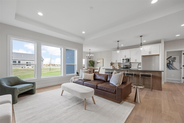 living room featuring ceiling fan with notable chandelier and light wood-type flooring