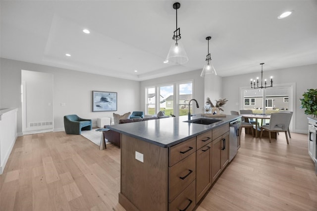 kitchen with a notable chandelier, sink, hanging light fixtures, and light wood-type flooring