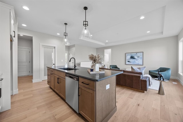 kitchen featuring dishwasher, a kitchen island with sink, hanging light fixtures, and light wood-type flooring