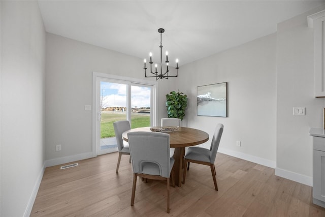 dining space with an inviting chandelier and light hardwood / wood-style floors