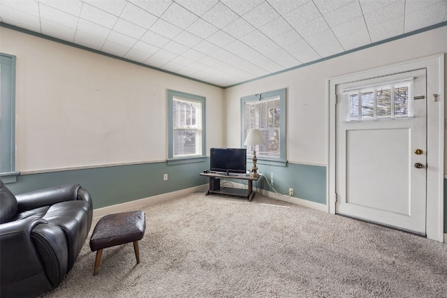 living area featuring carpet flooring, baseboards, and ornamental molding