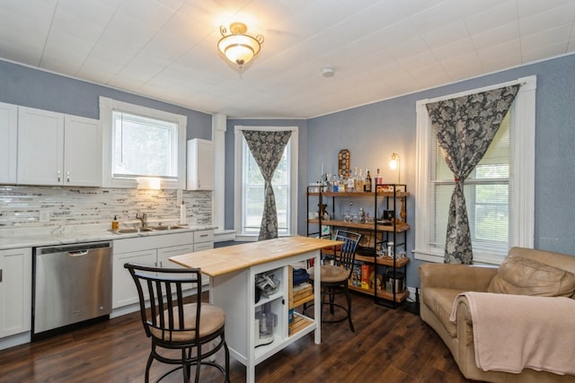 kitchen with backsplash, dark hardwood / wood-style flooring, white cabinets, and stainless steel dishwasher