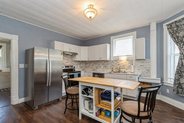 kitchen with appliances with stainless steel finishes, a kitchen island, backsplash, white cabinetry, and wooden counters