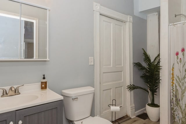 bathroom with toilet, vanity, and hardwood / wood-style floors