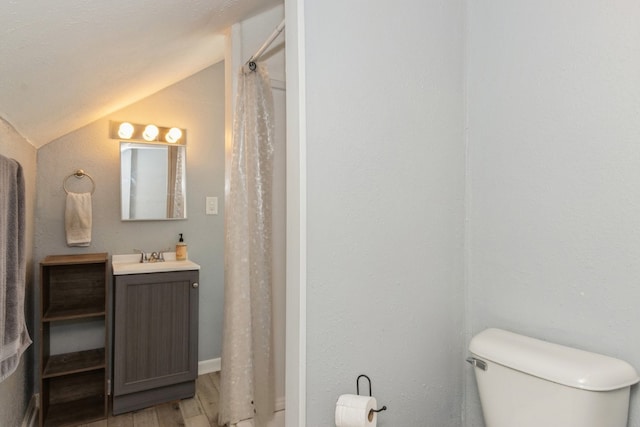 bathroom featuring hardwood / wood-style floors, vaulted ceiling, vanity with extensive cabinet space, and toilet