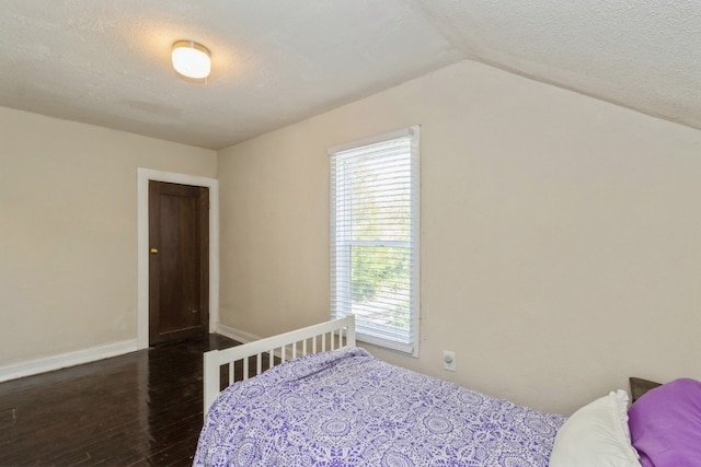 bedroom with dark hardwood / wood-style flooring, multiple windows, lofted ceiling, and a textured ceiling