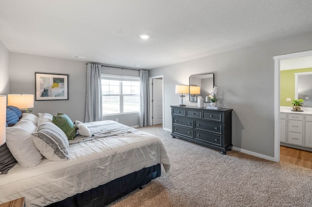 bedroom featuring a textured ceiling, light colored carpet, and connected bathroom