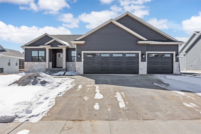 view of front facade featuring driveway, stone siding, an attached garage, and central air condition unit