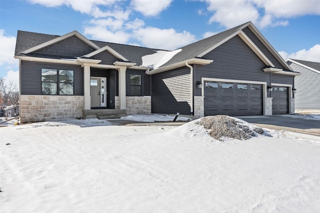 craftsman-style house featuring a shingled roof, stone siding, driveway, and an attached garage