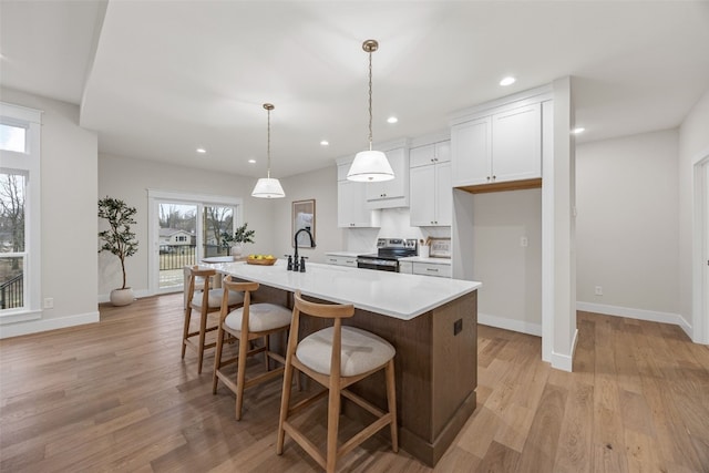 2733 Brookfield Dr, Marion, IA 52302 - kitchen featuring stainless steel range with electric cooktop, light countertops, white cabinetry, a kitchen breakfast bar, and an island with sink