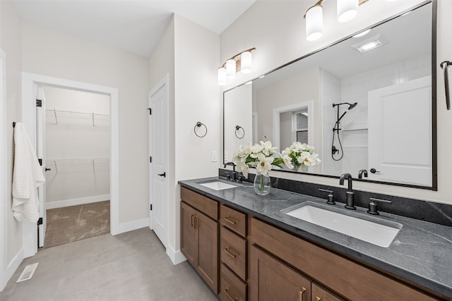 2733 Brookfield Dr, Marion, IA 52302 - bathroom featuring double vanity, a tile shower, a walk in closet, and baseboards