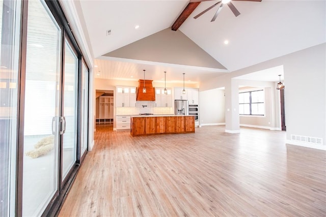 unfurnished living room featuring beam ceiling, high vaulted ceiling, light hardwood / wood-style floors, and ceiling fan with notable chandelier