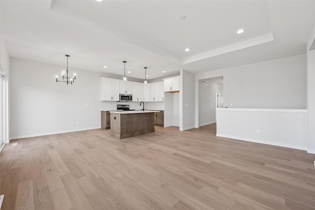 kitchen featuring hanging light fixtures, a center island, stainless steel appliances, a tray ceiling, and white cabinetry