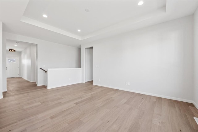 spare room with light wood-type flooring and a raised ceiling