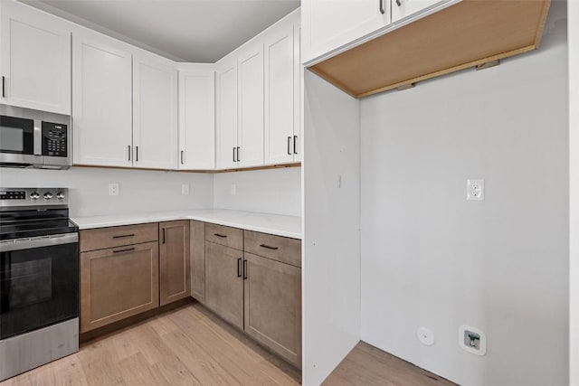 kitchen featuring appliances with stainless steel finishes, light hardwood / wood-style flooring, and white cabinets