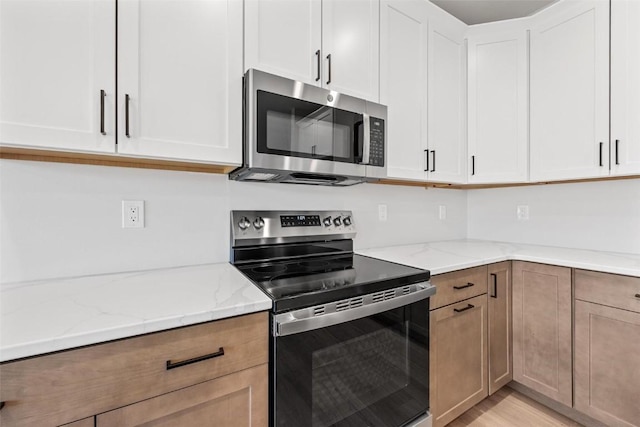 kitchen featuring white cabinets, light stone counters, and appliances with stainless steel finishes