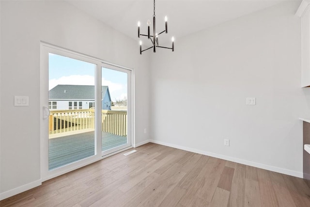 unfurnished dining area featuring light wood-type flooring, a notable chandelier, and a wealth of natural light