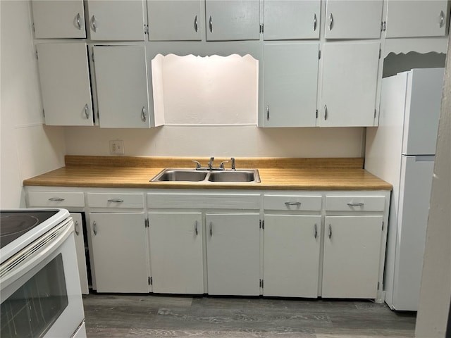 kitchen featuring white appliances, sink, white cabinets, and wood-type flooring