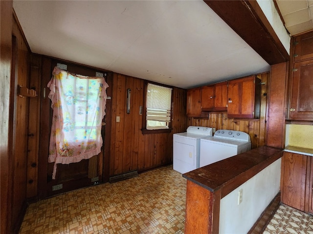 laundry room featuring washer and dryer, wood walls, light tile flooring, and cabinets