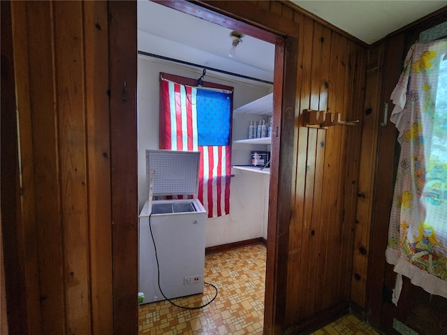 laundry area featuring wood walls and light tile flooring