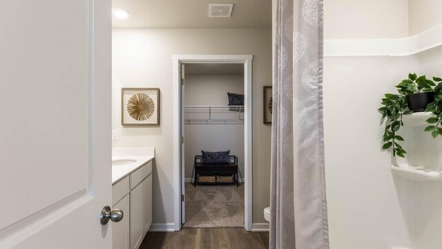 bathroom with wood-type flooring, toilet, and vanity