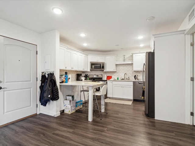 kitchen with stainless steel appliances, white cabinets, tasteful backsplash, and dark wood-type flooring