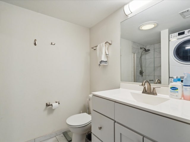 bathroom featuring tile flooring, stacked washing maching and dryer, toilet, and vanity