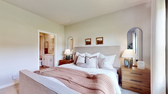 bedroom featuring connected bathroom and light colored carpet