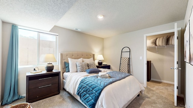 bedroom featuring a closet, light colored carpet, a spacious closet, and a textured ceiling