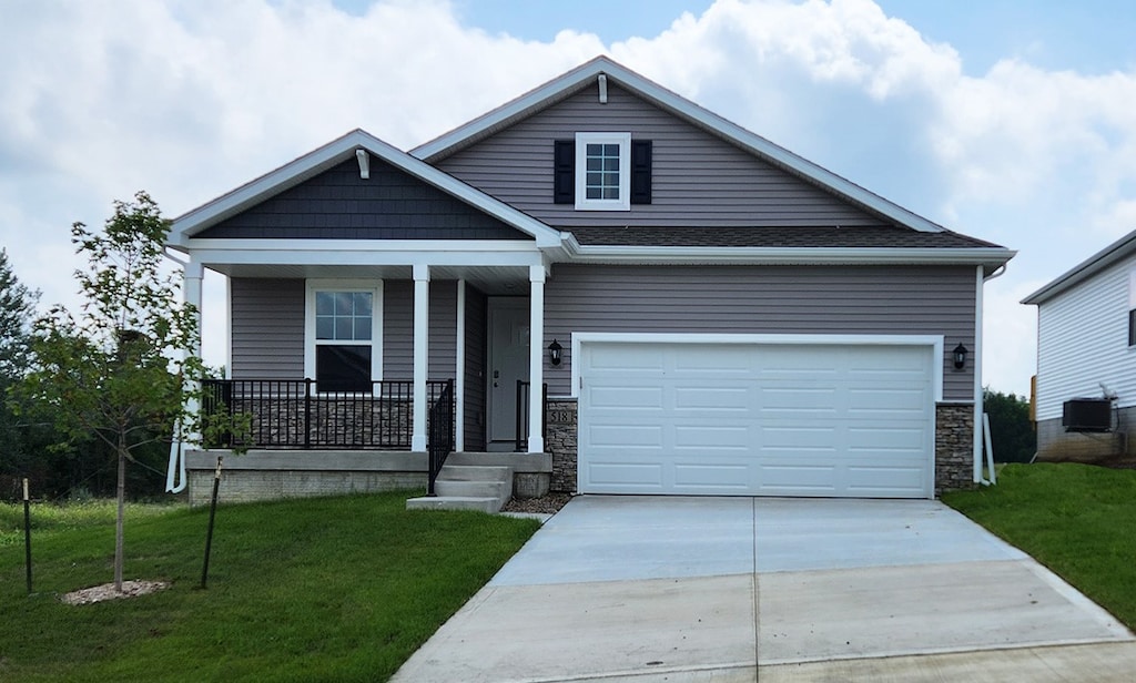 craftsman-style house with central AC unit, a garage, covered porch, and a front yard