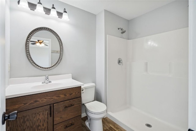 bathroom featuring vanity, ceiling fan, a shower, and toilet