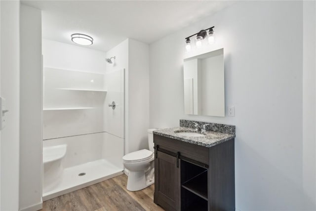 bathroom with wood-type flooring, vanity, toilet, and walk in shower