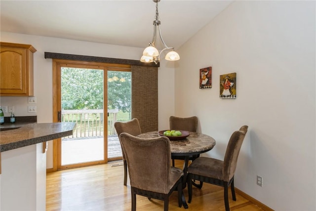 dining room with a chandelier, light wood-type flooring, and vaulted ceiling