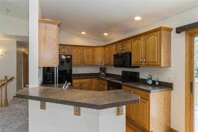 kitchen featuring a kitchen bar, kitchen peninsula, black appliances, and lofted ceiling