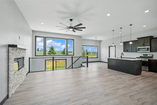 kitchen featuring a center island with sink, pendant lighting, light wood-type flooring, and appliances with stainless steel finishes