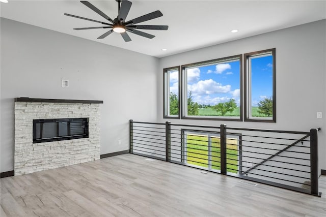 unfurnished living room with ceiling fan, a fireplace, and light hardwood / wood-style floors