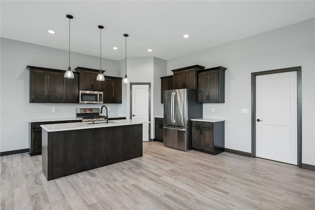 kitchen with pendant lighting, an island with sink, dark brown cabinets, light hardwood / wood-style floors, and stainless steel appliances